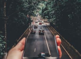 Forced Perspective Photography of Cars Running on Road Below Smartphone