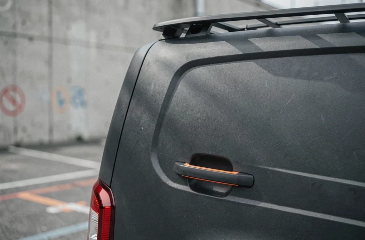 Détail du panneau arrière et du porte-bagages du concept Dacia Sandman avec cladding plastique texturé et accents oranges