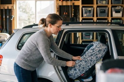 Jeune maman installant un couvre-siège auto dans une voiture