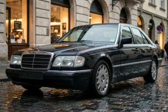 Mercedes-Benz S600 W140 V12 noire garée sur pavés mouillés dans une rue européenne, reflets sur la carrosserie