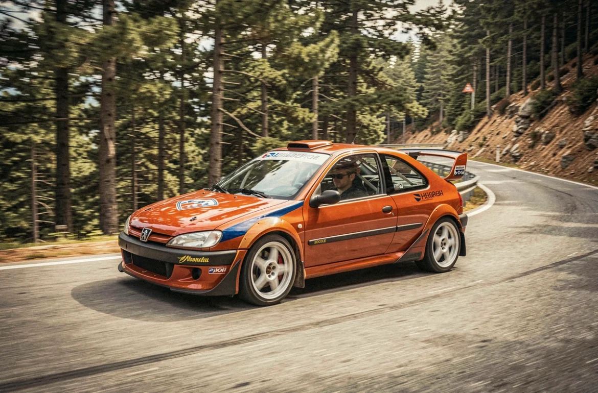 Peugeot 306 réplique Maxi en pleine action sur une route de montagne, vue de profil en virage avec forêt en arrière-plan