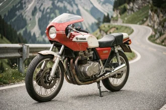 Yamaha RDLC 350 occasion garée sur une route de montagne sinueuse, vue 3/4 avant révélant le moteur deux-temps et les pipes d'expansion emblématiques
